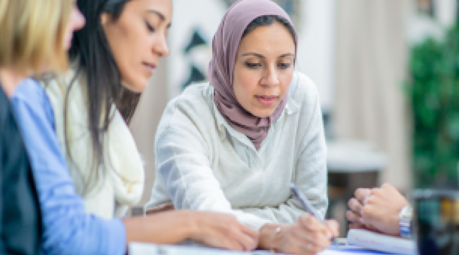 A group of ladies gathered around a table looking at documents