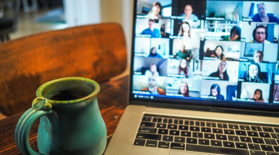 laptop showing a video conference, with a cup of coffee next to the laptop